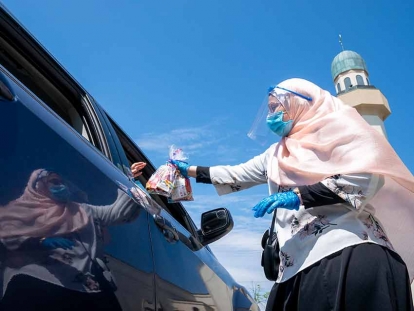 An Islamic Society of North America Mosque community member hands out candy to children in a drive-through Eid celebration in Mississauga, Ont., on May 24, 2020