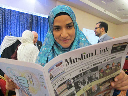 Dalia Mogahed reading a copy of Muslim Link at the National Council of Canadian Muslims fundraising dinner in Ottawa.