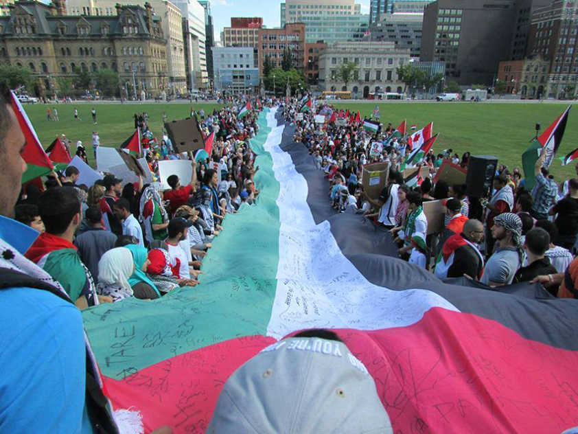 Demonstrators hold Palestinian flag at Parliament Hill