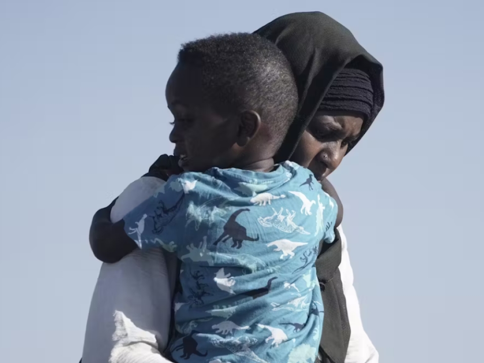 A Sudanese refugee carries her son as they arrive in Jeddah port, Saudi Arabia, in May 2023. Sudan has been torn by civil war for more than a year, resulting in a humanitarian crisis.