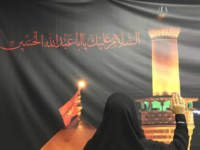 A banner like this is found in many Twelver Shia mosques. The words in red read « Al Salaam Aleika ya Aba Abdilla Al Hussain (Peace be on you, Hussain father of Abdallah) ». The hand gesture is symbolic., it&#039;s a form of salutation to  Imam Hussain (pbuh) and to those who have suffered on Ashura. This hand gesture is make when Shia Muslims read a type of prayer called  a « Ziyarat ». The prayer is taken from the Quran : &quot;And never think of those who have been killed in the cause of Allah as dead. Rather, they are alive with their Lord, receiving provision&quot; 3:169.