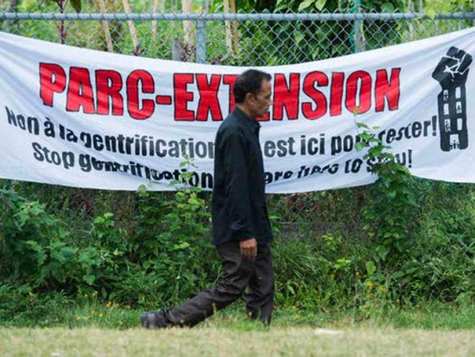 A man walks past a sign in Montreal’s Parc-Extension neighbourhood in August 2019, during a community event where people voiced their concerns about gentrification in the multicultural borough.