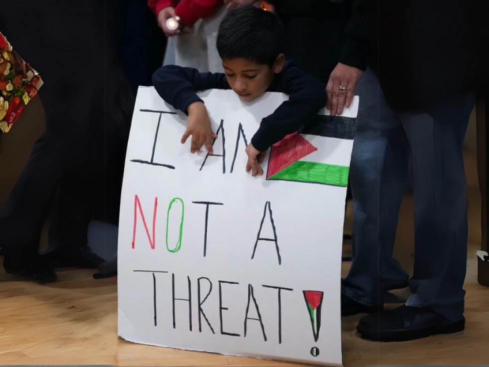 A boy holds a sign during a vigil for six-year-old Palestinian-American Wadea Al-Fayoume. An Illinois landlord was accused of fatally stabbing the boy and seriously wounding his mother and was charged with a hate crime.