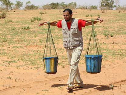 Zaid Al Rawni carries heavy buckets from the oasis to a village in Niger, mimicking the walk the people of the village have to carry out daily - the strain of the heavy weight visible on his face.