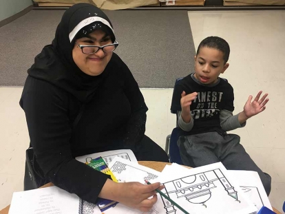 Aaliya Jaffer volunteers to help Mikail Abbas with his craft project during Muharram 2018 at the Jaffari Community Centre.