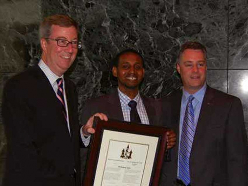 Mohamed Sofa (middle) holds his award and poses with Mayor Jim Watson (left) and Bay Ward Councillor Mark Taylor (right).