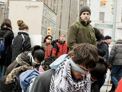 Actors kneel in line at a mock Israeli checkpoint recreated in Ottawa.
