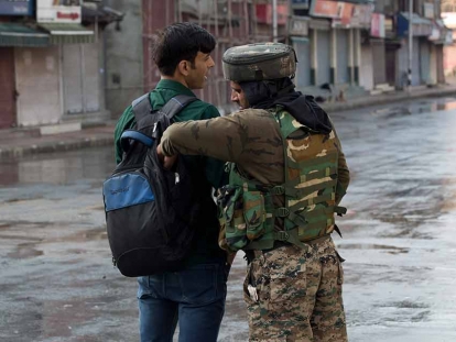 An Indian paramilitary soldier checks the bag of a Kashmiri man during curfew in Srinagar, Indian-controlled Kashmir. 